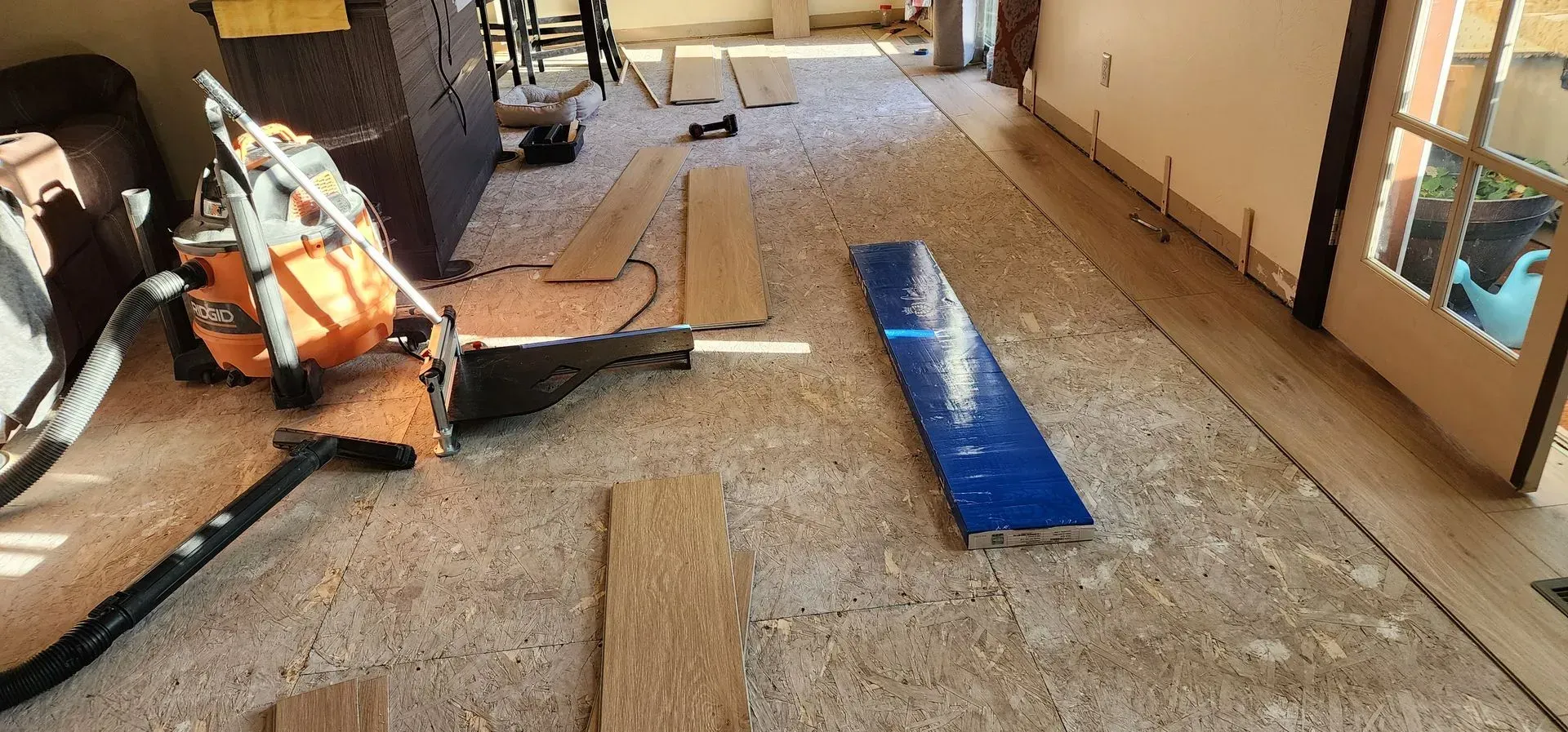 A room with a lot of wood and a saw on the floor.