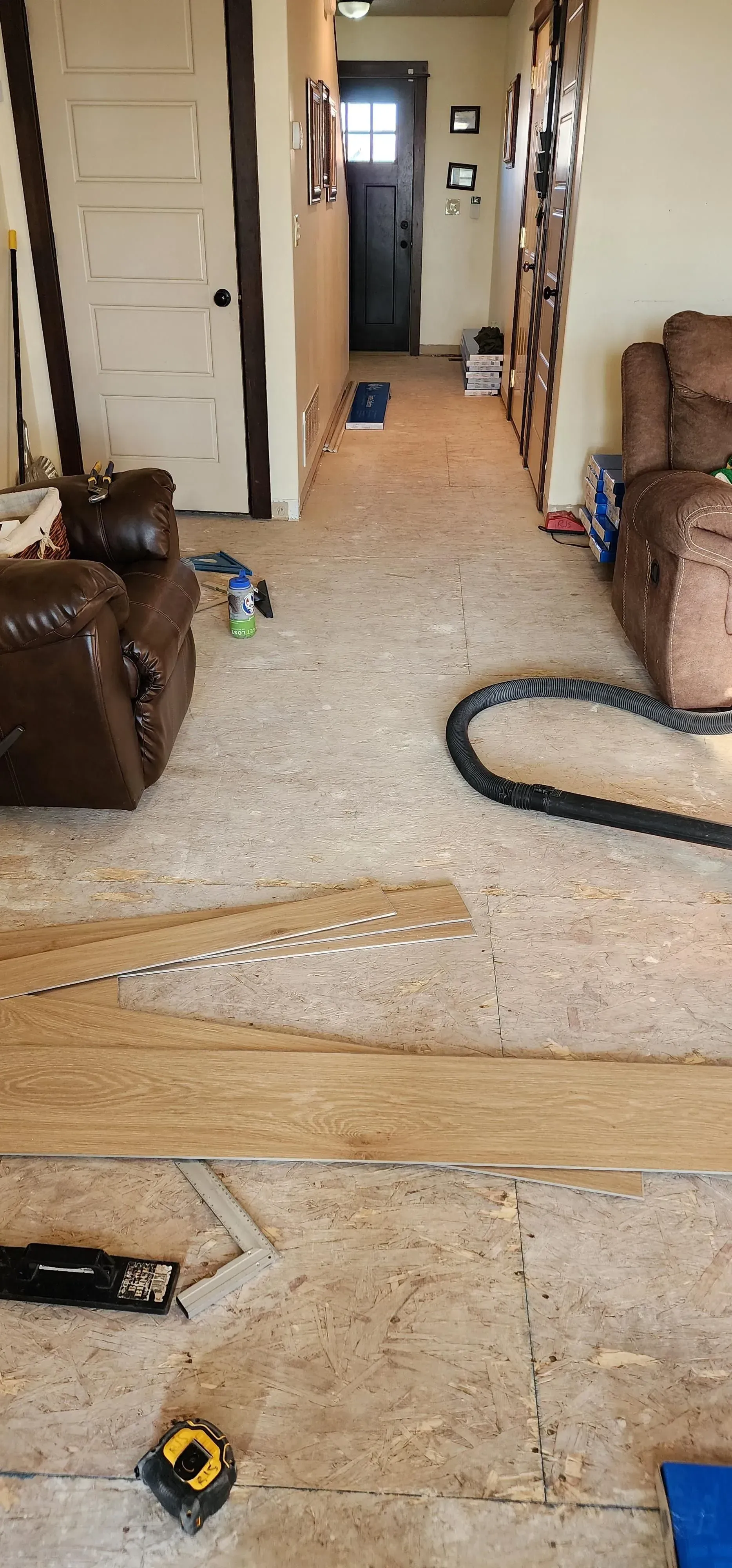 A living room with a couch , chair , and measuring tape on the floor.