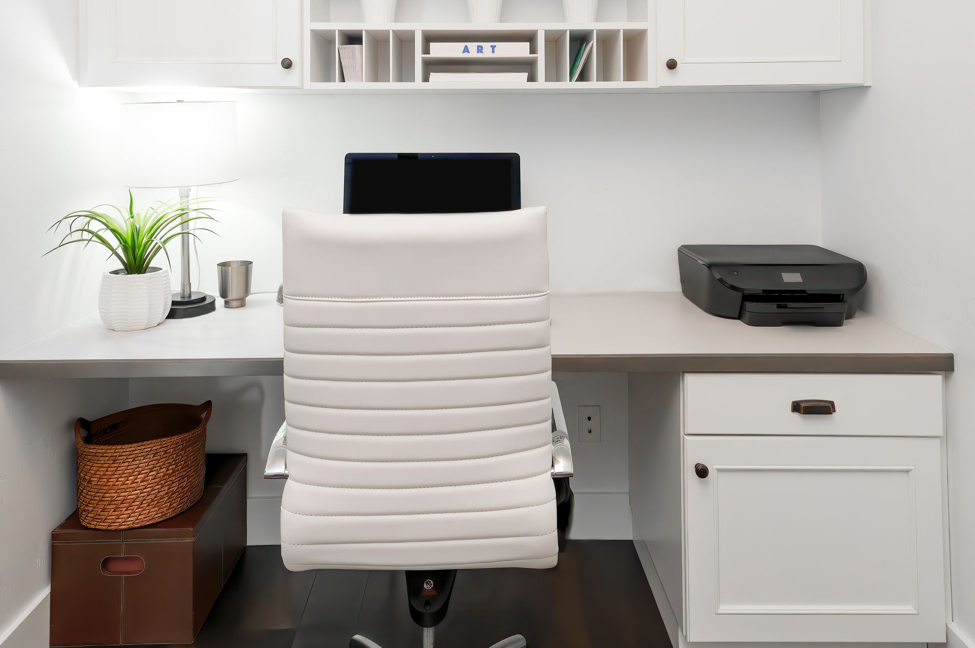White office desk with a chair, printer, and overhead storage.