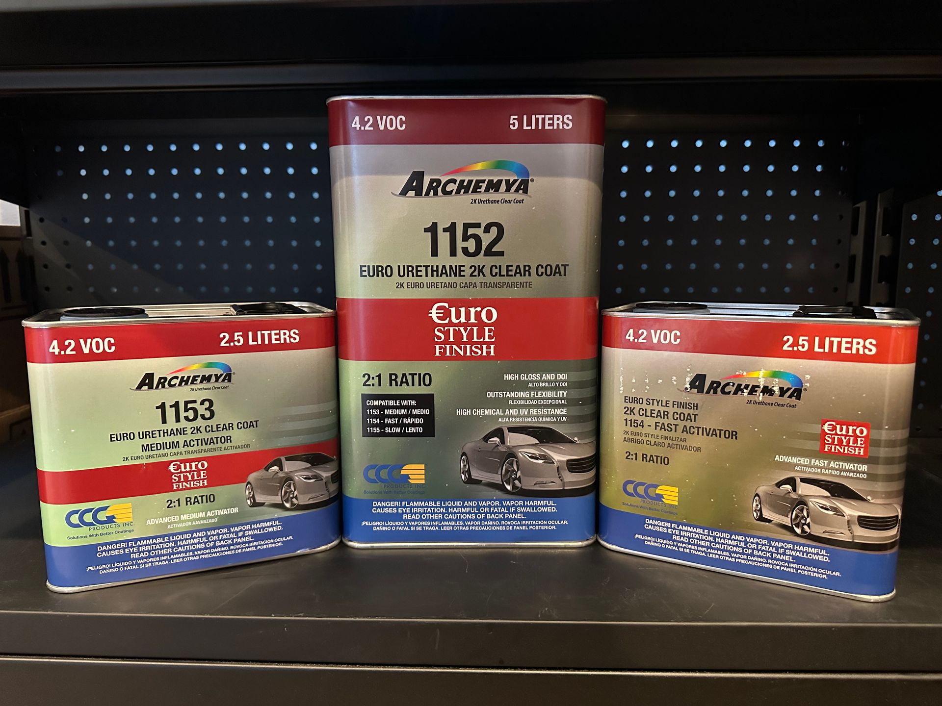 Three cans of auto paint are sitting on a shelf.