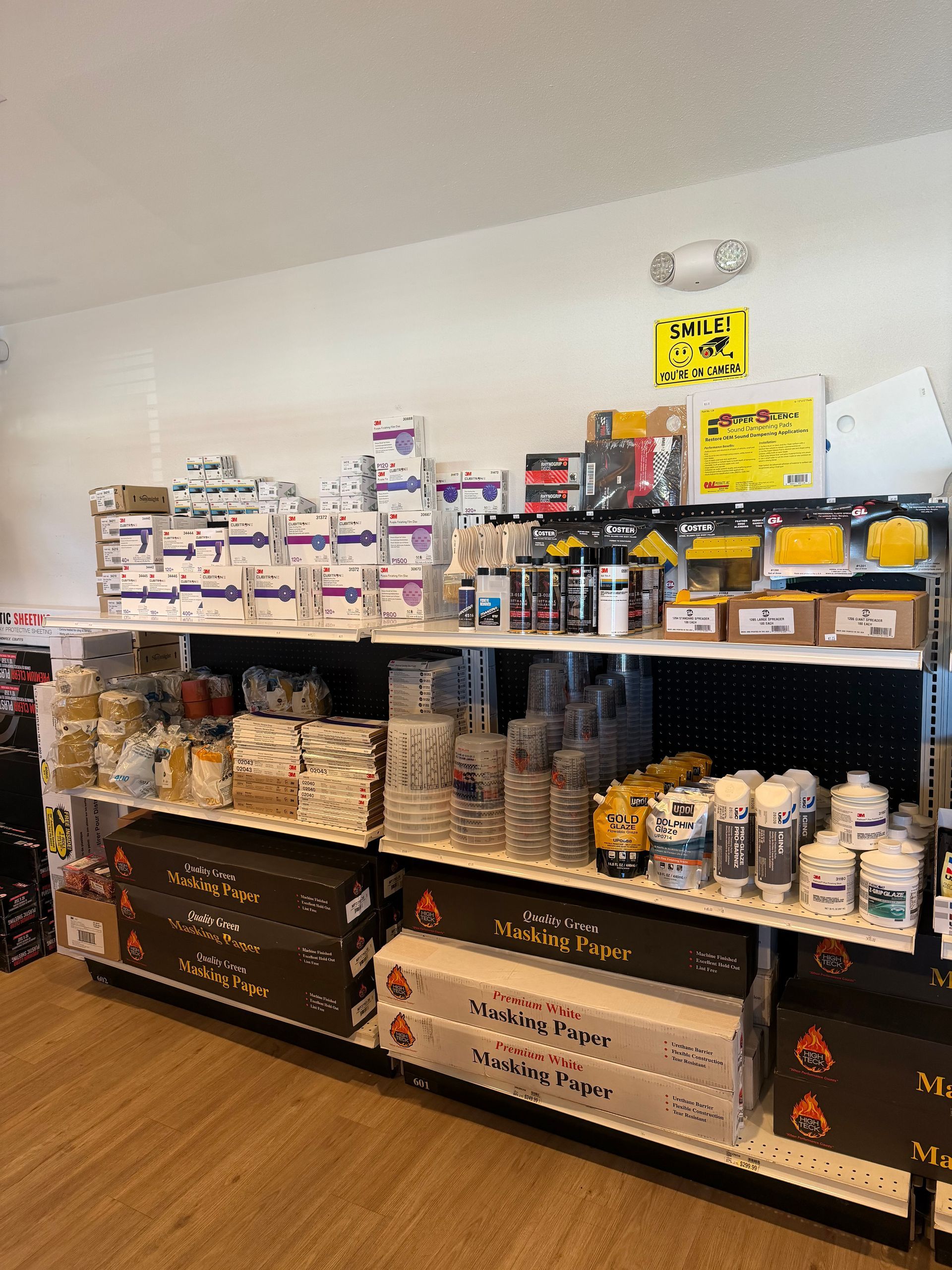 Shelves stocked with various products in a store. White, beige, and yellow tones.