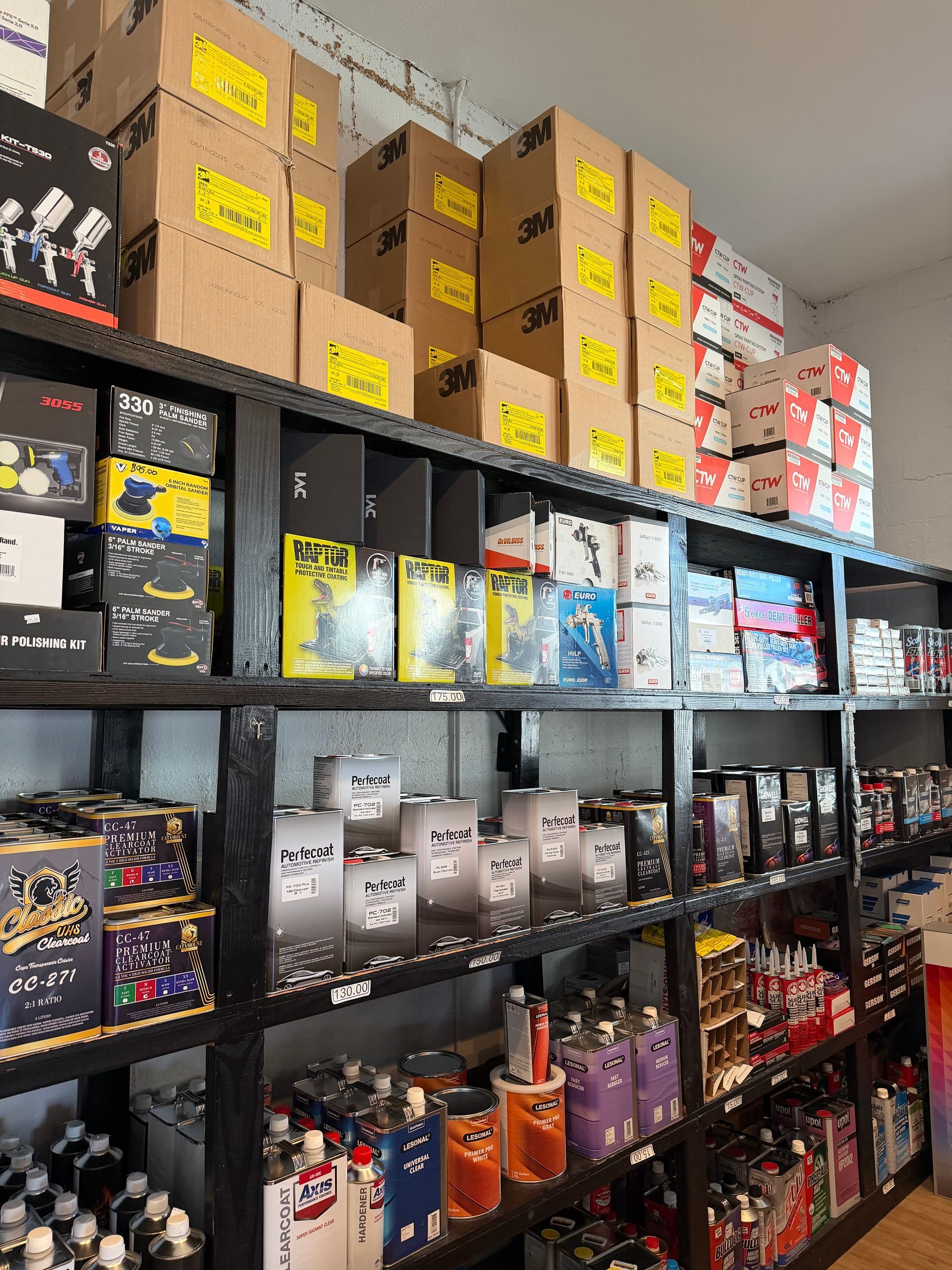 Shelves in a store filled with packaged goods, including boxes and cans, against a white wall.