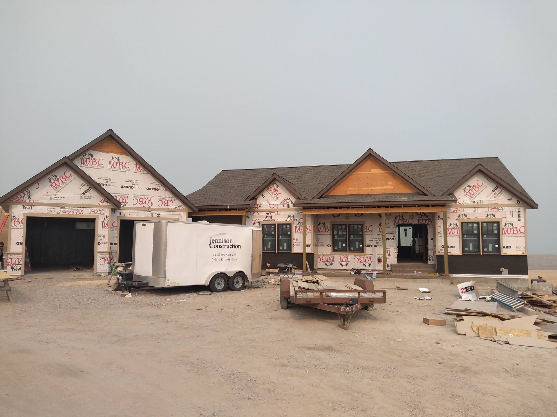 A large house under construction with a trailer parked in front of it.