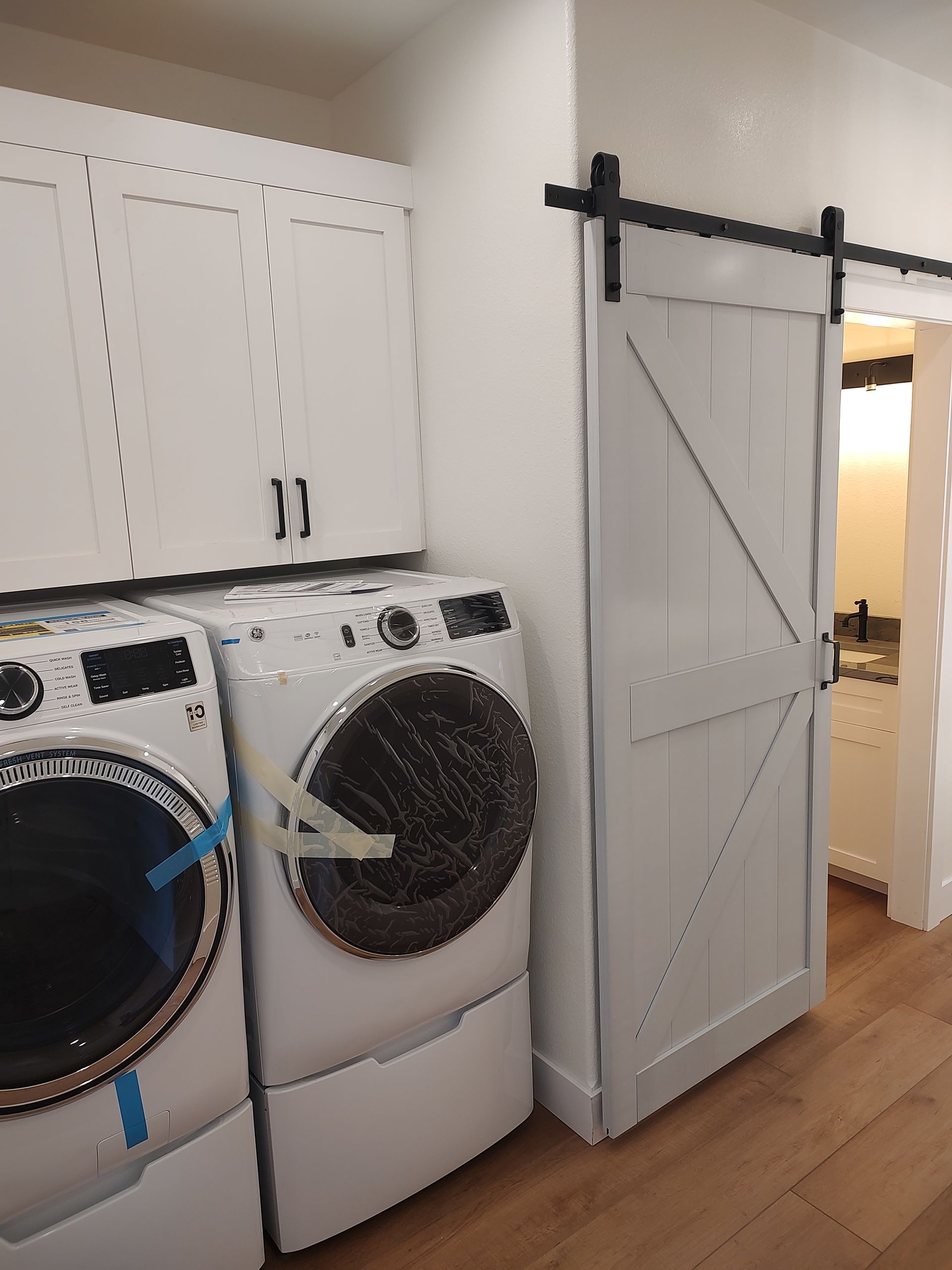A laundry room with a washer and dryer and a sliding barn door.