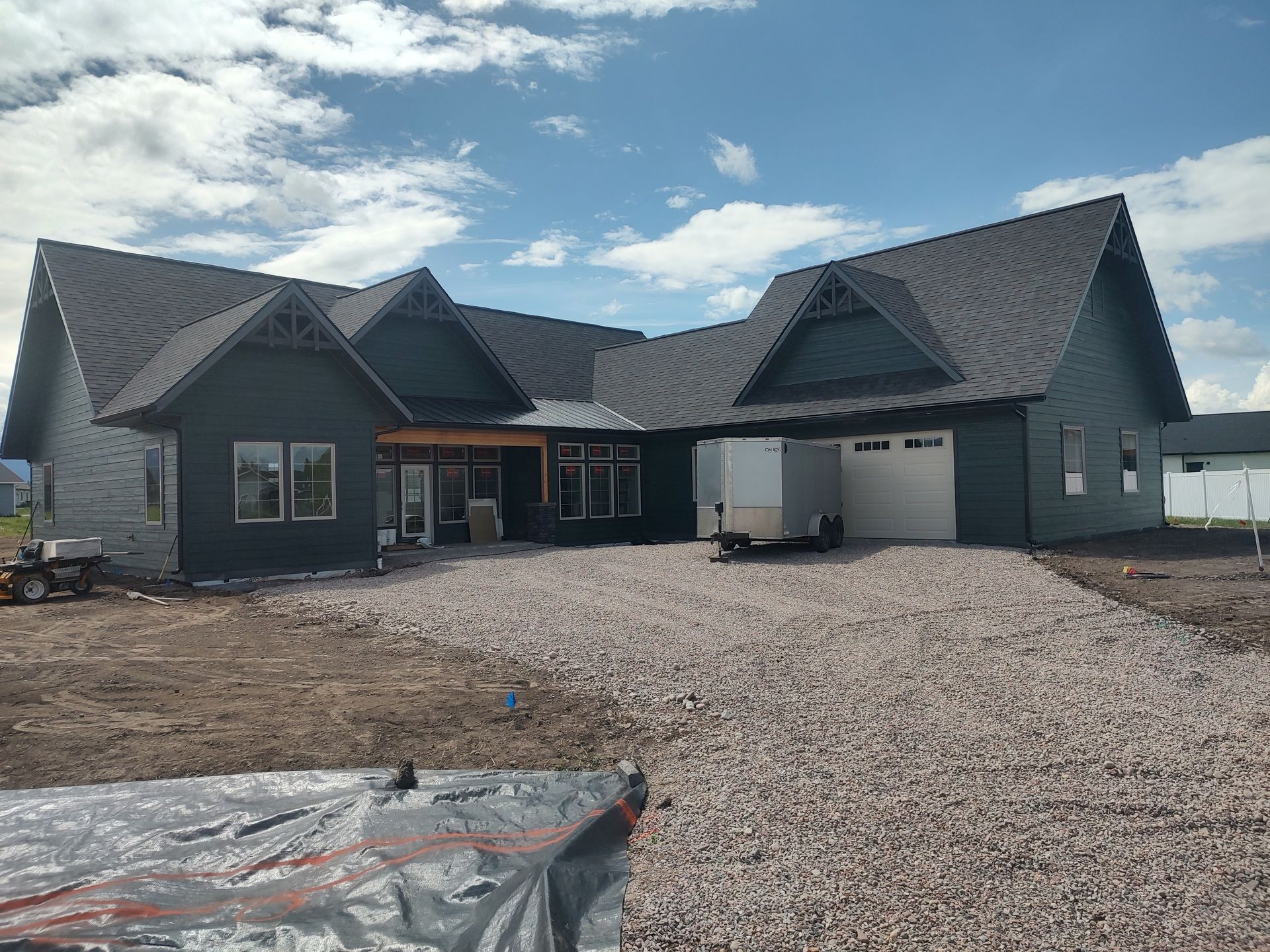 A large house with a gravel driveway in front of it is being built.