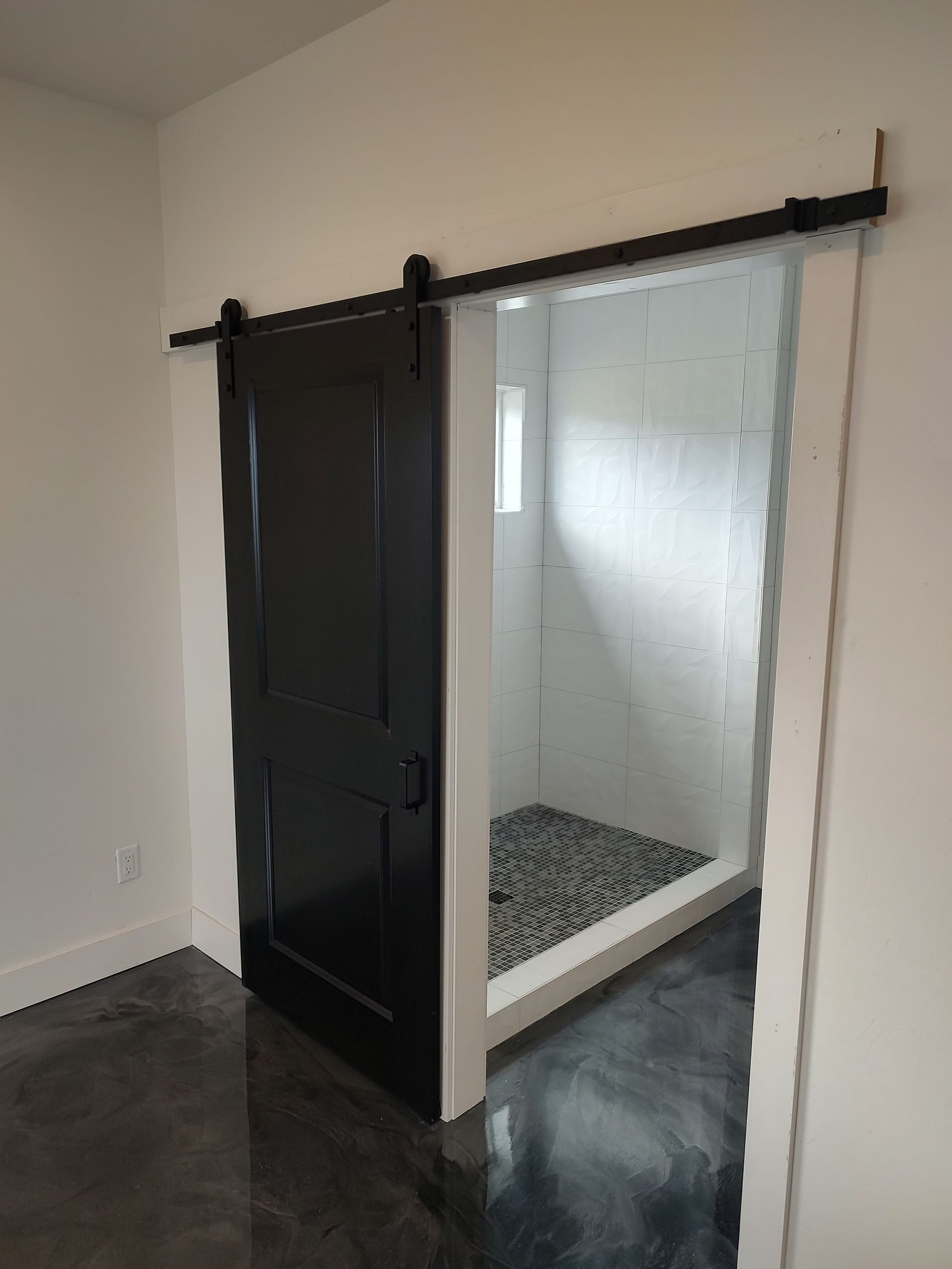 A black sliding barn door is open to a bathroom.