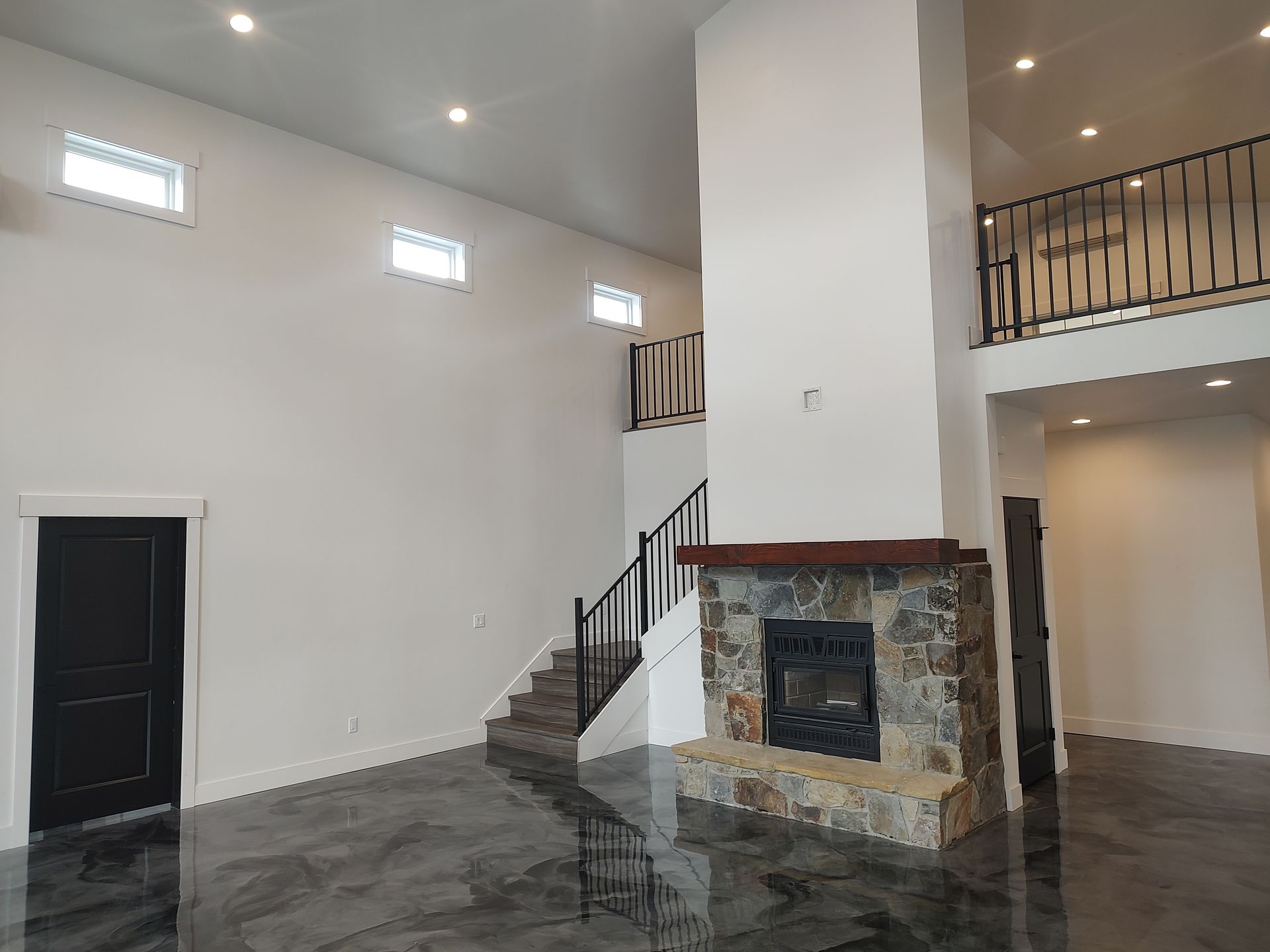 A large empty room with a fireplace and stairs.