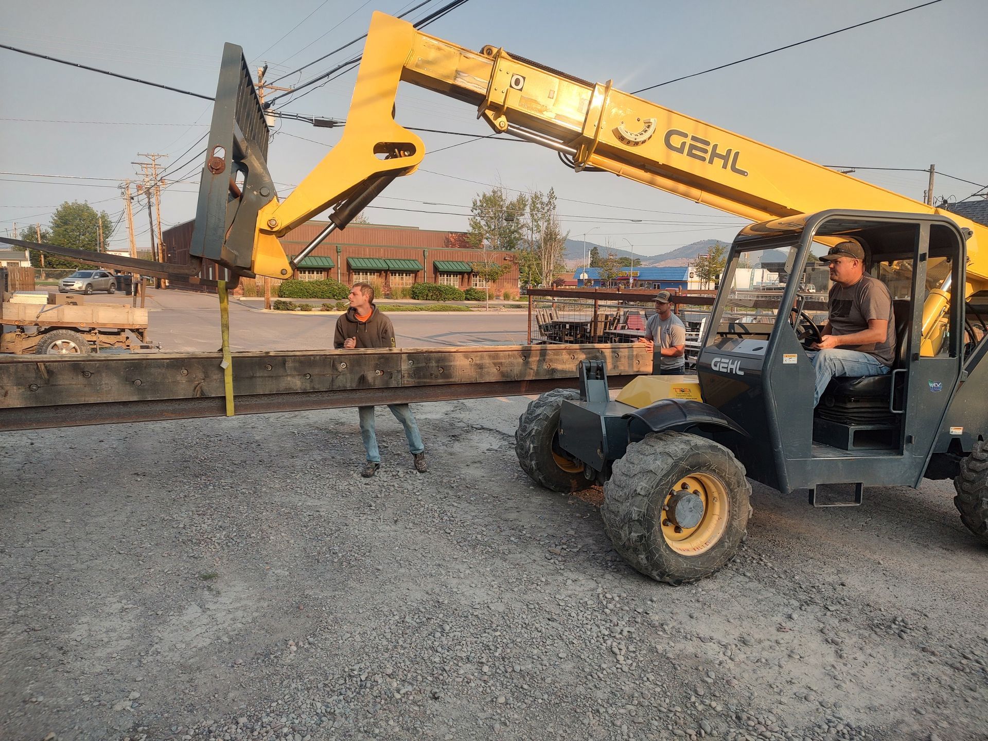 A man is standing next to a yellow forklift that says gehl on it.