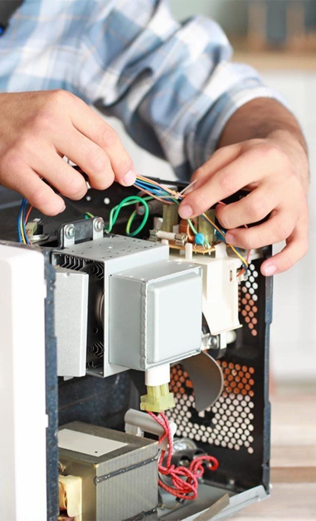 Worker Repairing Microwave — Jason Wenta Electrical Services in Condon, QLD