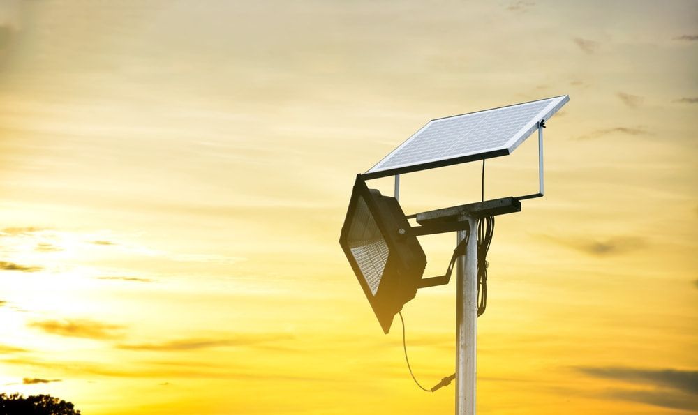 A Solar Panel Is Sitting on Top of A Pole with A Sunset in The Background — Jason Wenta Electrical Services in Condon, QLD
