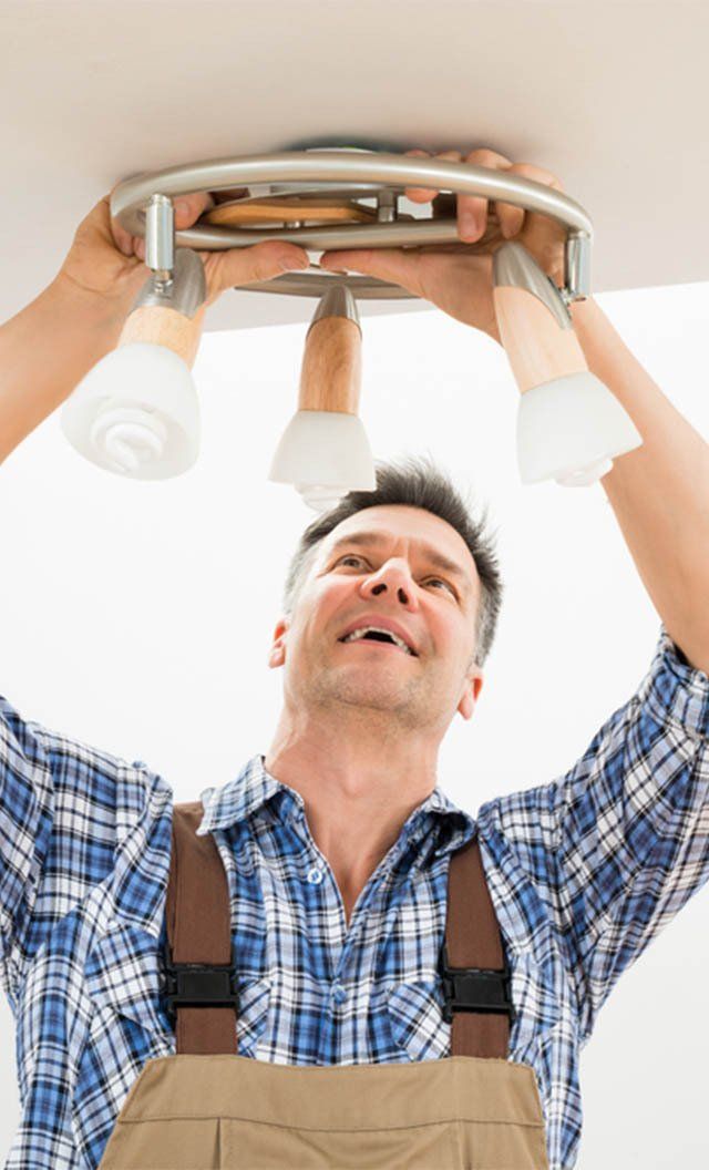 Portrait of a Male Electrician Fixing Light — Jason Wenta Electrical Services in Condon, QLD