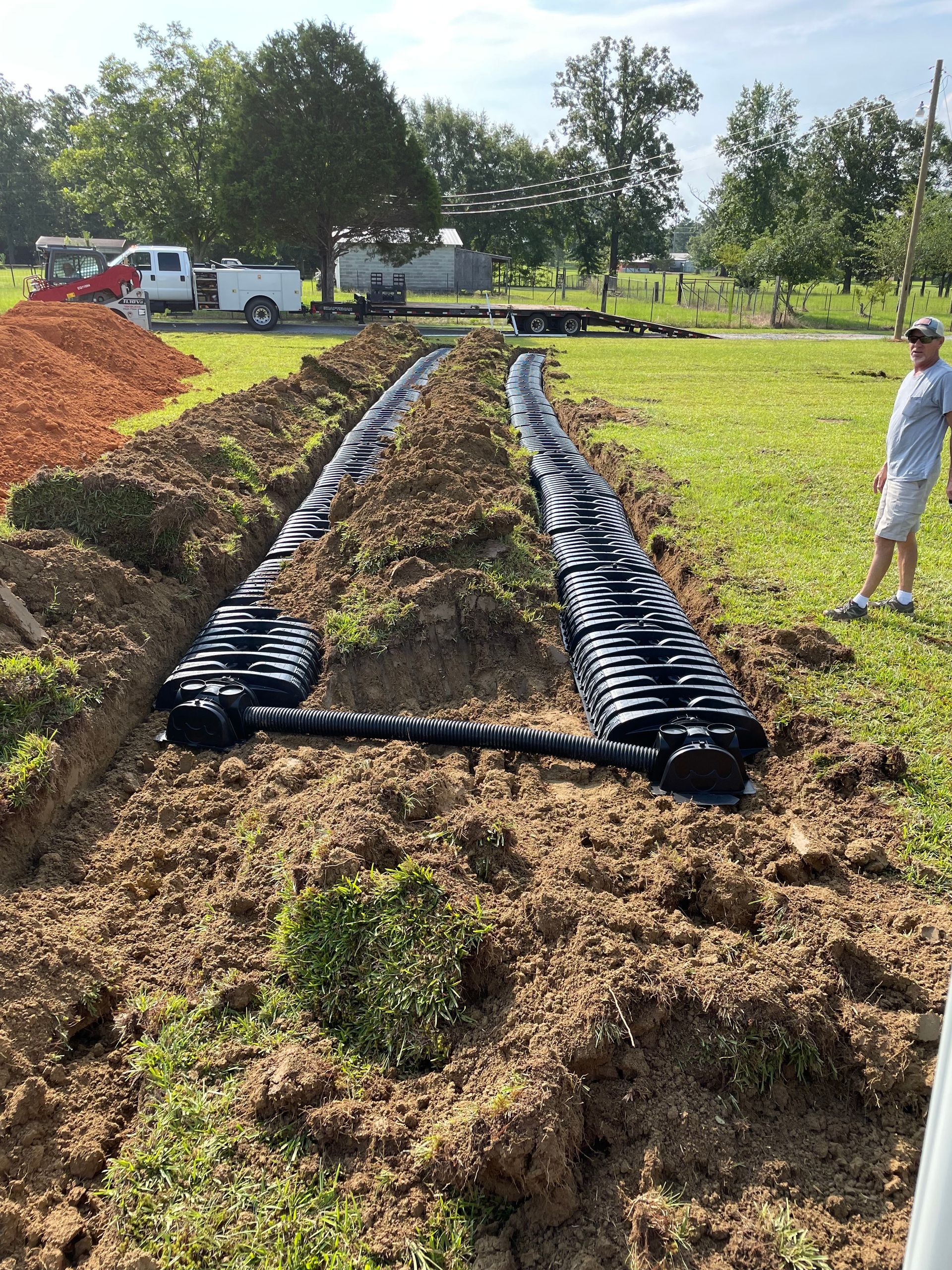 A man is standing in a field next to a large pile of dirt.
