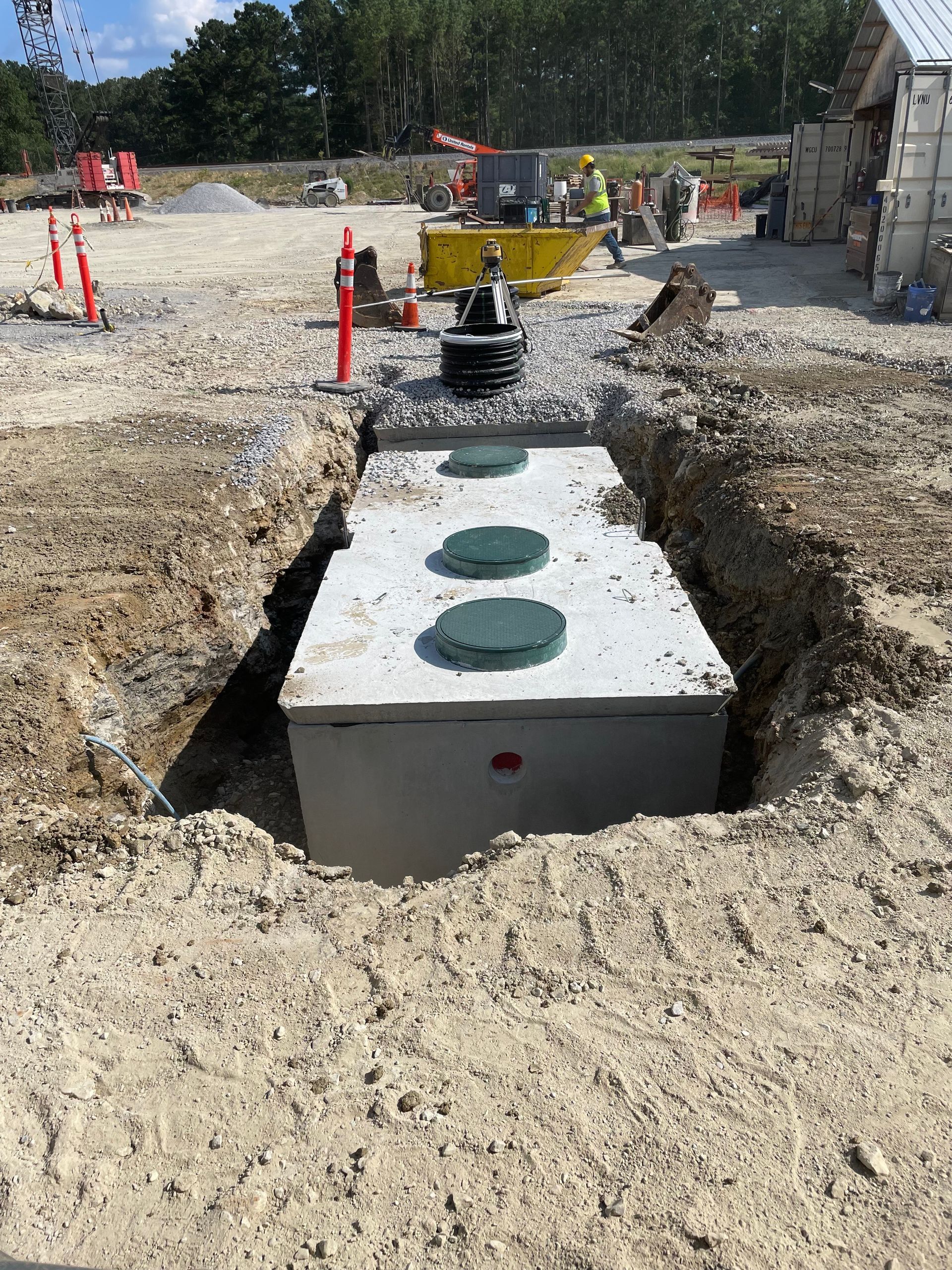 A septic tank is being installed in the dirt in a construction site.
