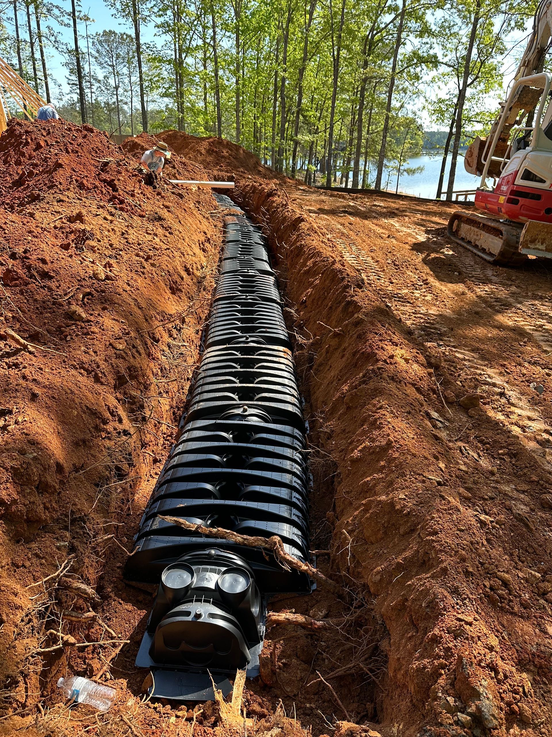 A large pipe is being installed in a trench in the dirt.