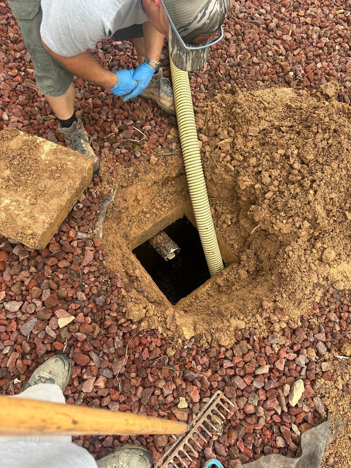A man is pumping water into a hole in the ground.