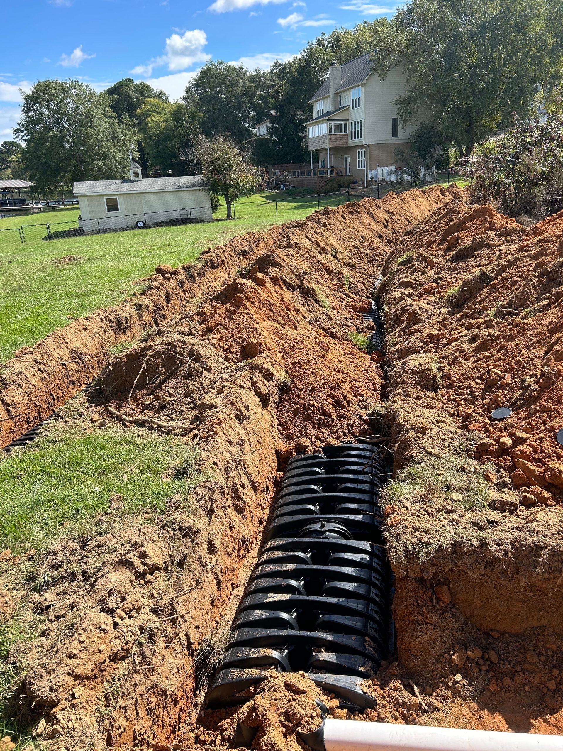 A septic system is being installed in a yard next to a house.