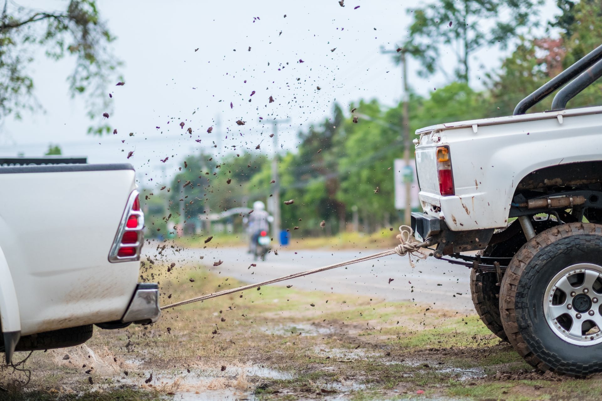 Woman in straw hat smiles, holding wine glass near a lake.