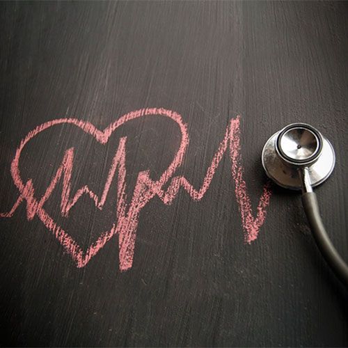 A stethoscope is sitting next to a heart drawn on a blackboard.