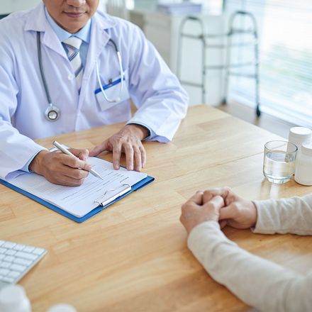 A doctor is sitting at a table talking to a patient.