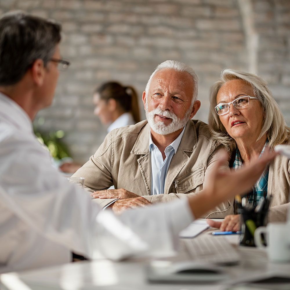 A man and a woman are sitting at a table talking to a doctor.