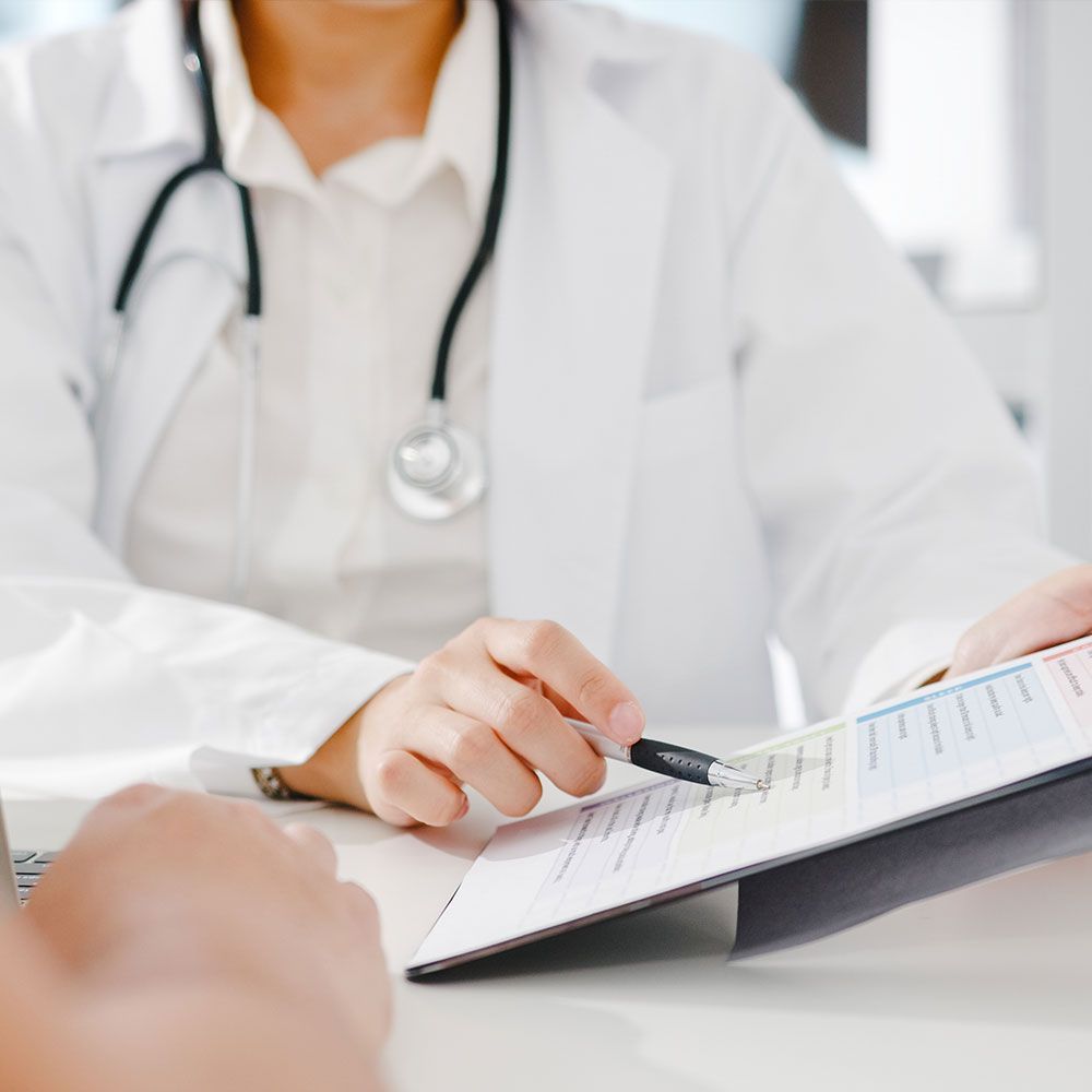 A doctor is talking to a patient while holding a clipboard.