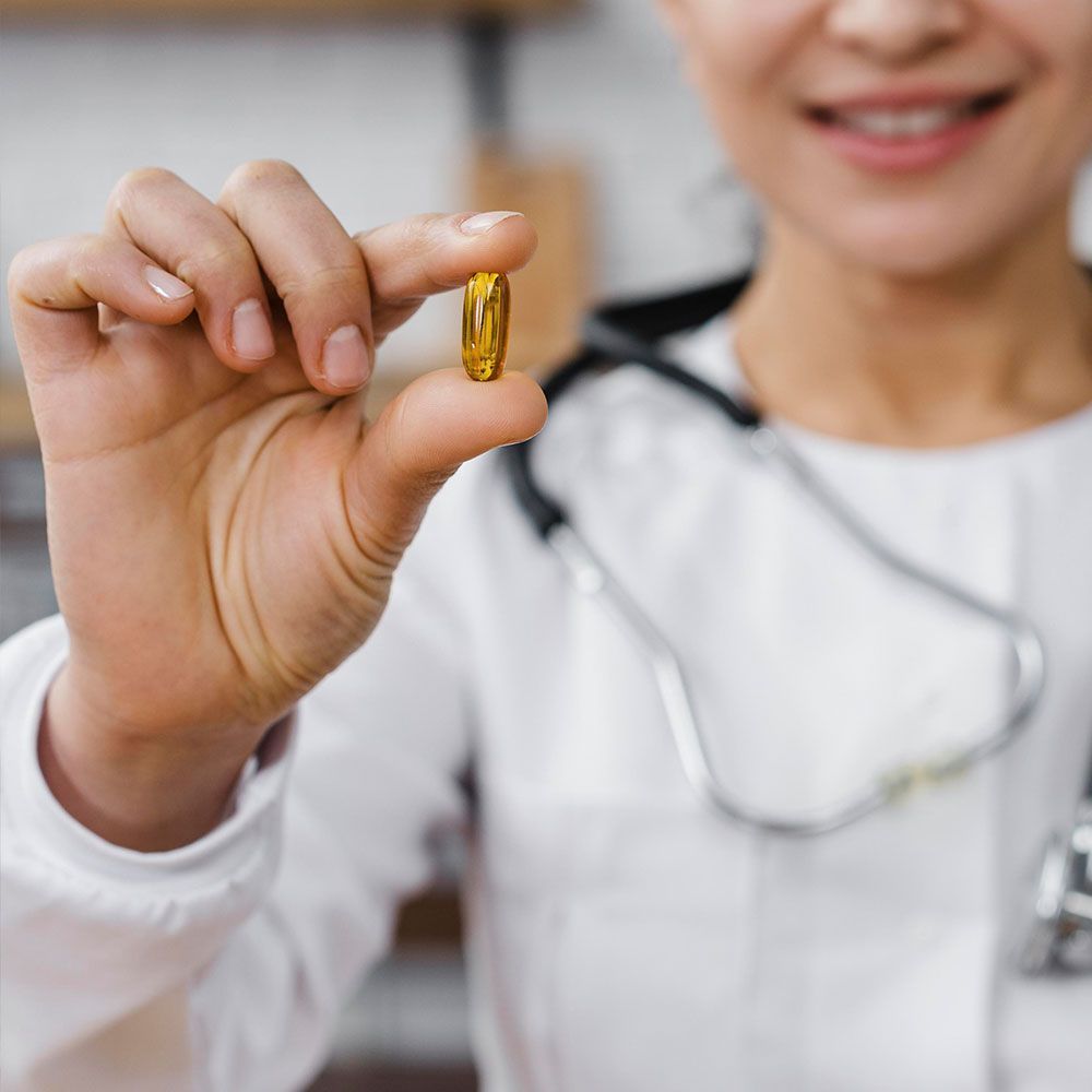 A doctor is holding a yellow pill in her hand.