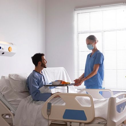 A nurse is talking to a patient in a hospital bed.