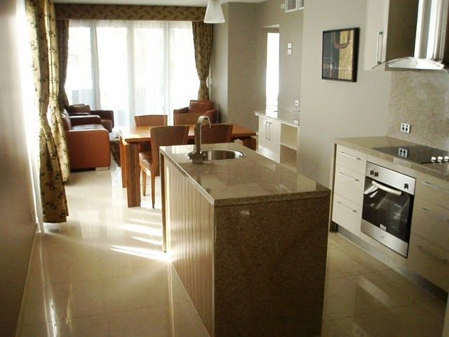 Modern kitchen and dining area with island, white cabinets, and sunlight from large windows