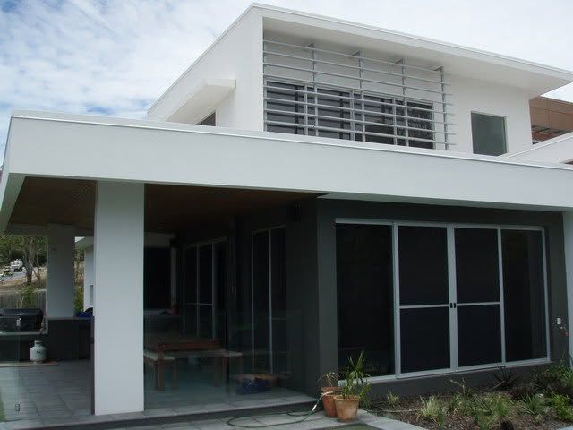Modern white house with large glass windows and a covered patio