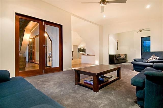 Modern living room with dark teal sofas, a coffee table, large mirror, and white walls