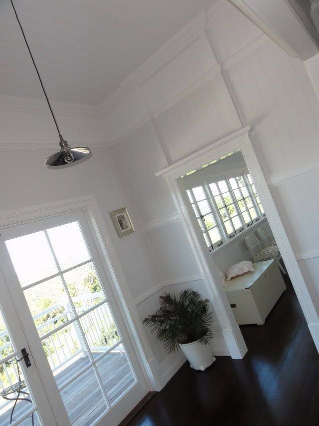Bright white room with glass doors, dark wood floor, plant, and built-in bench nook