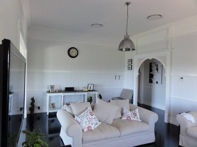 Bright living room with white sofa, sideboard, wall clock, and arched doorway