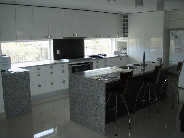 Modern kitchen with white cabinets, granite island, and black bar stools