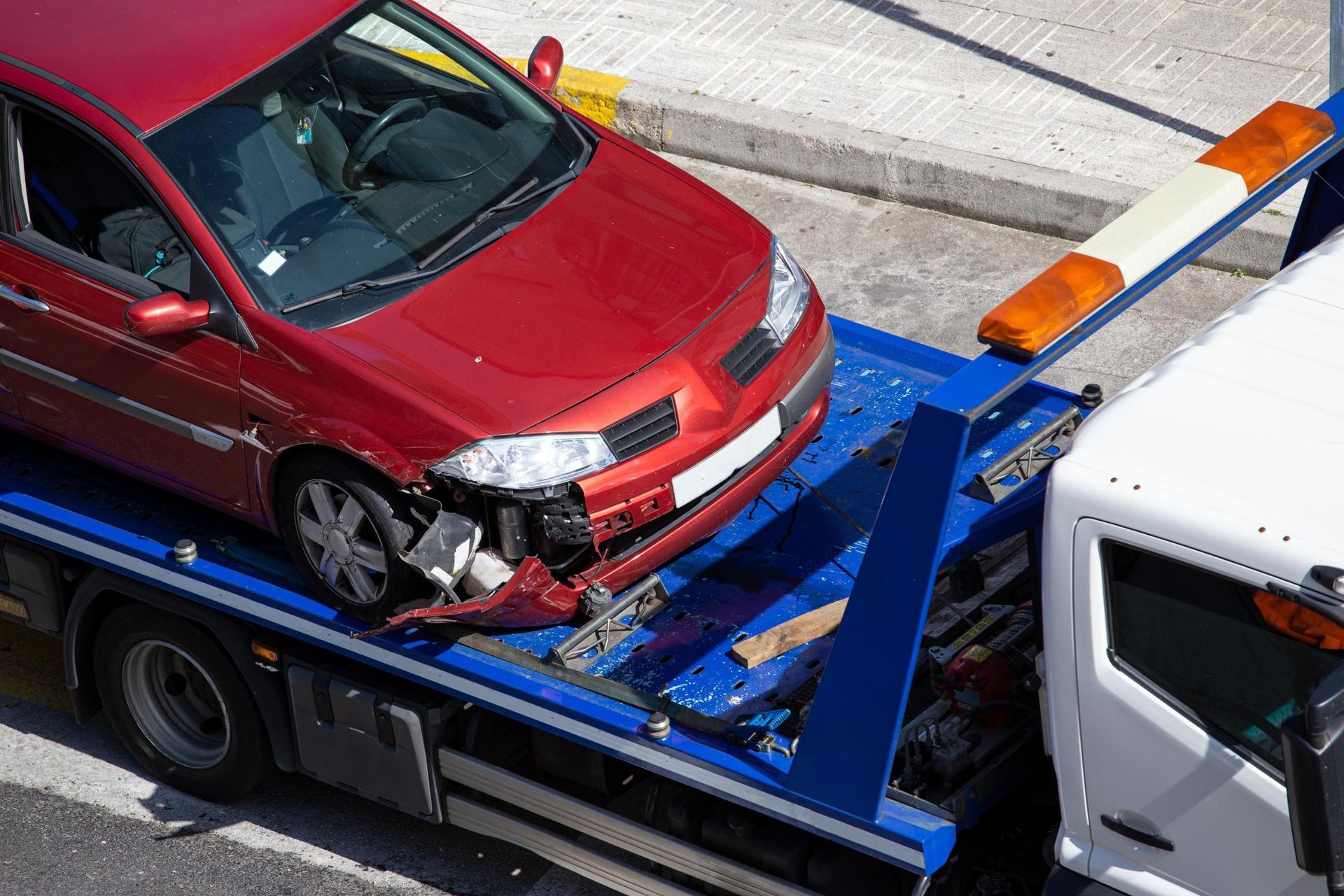 A red car is being towed by a tow truck.