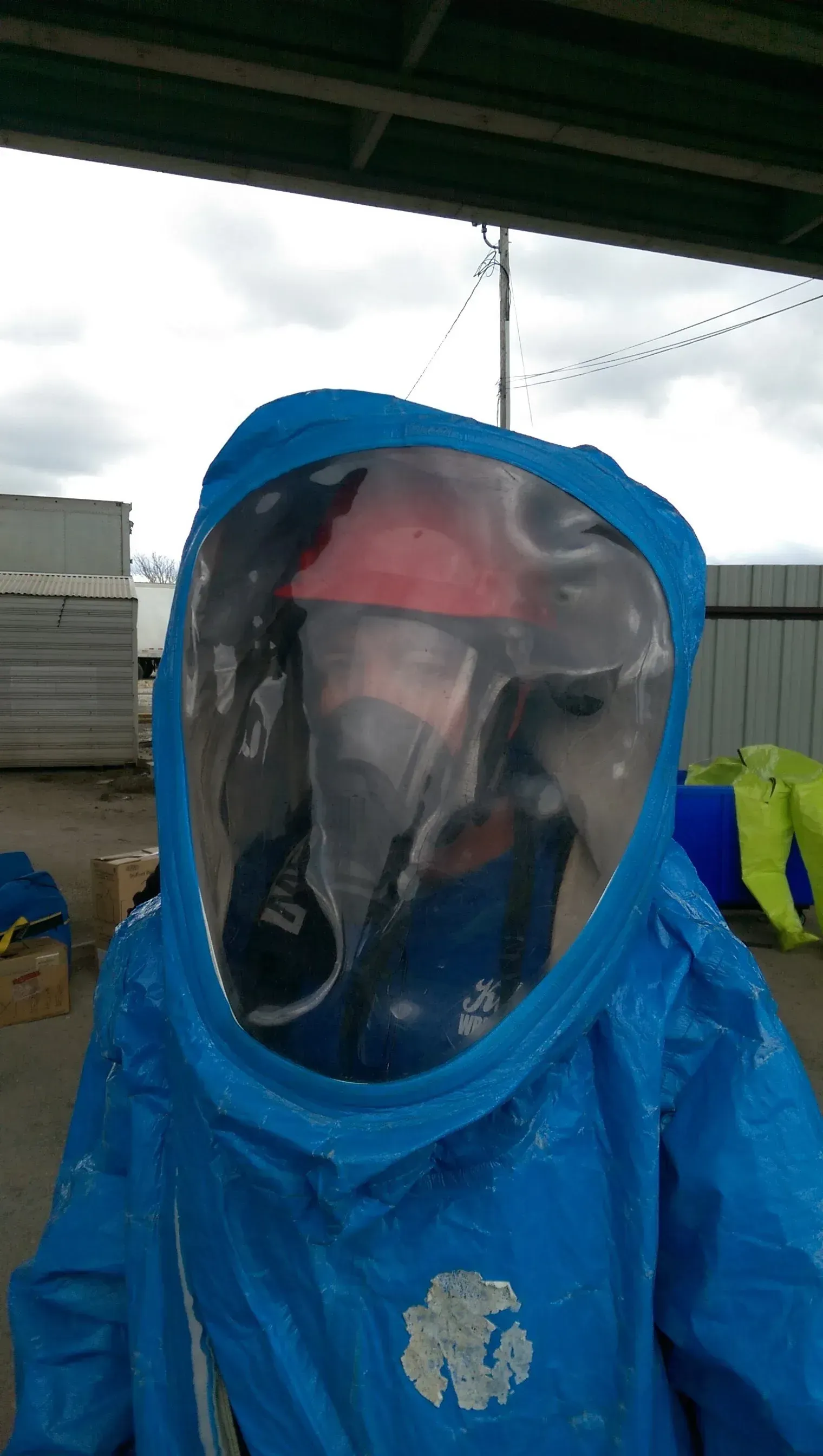 A person wearing a blue protective suit with a helmet on their head.