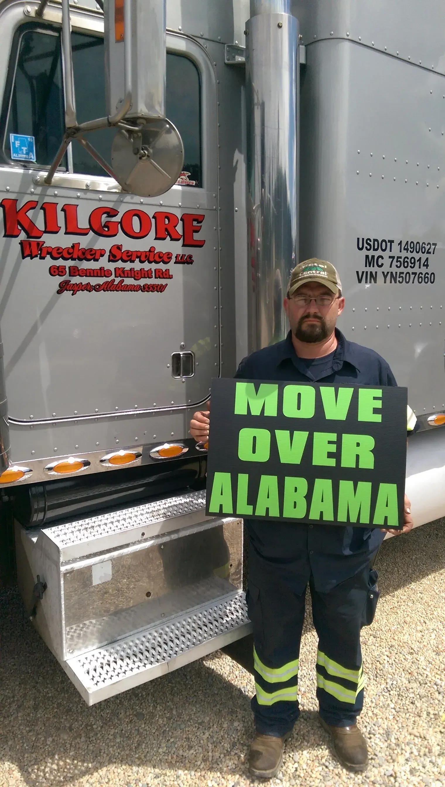 A man is holding a sign that says `` move over alabama '' in front of a truck.