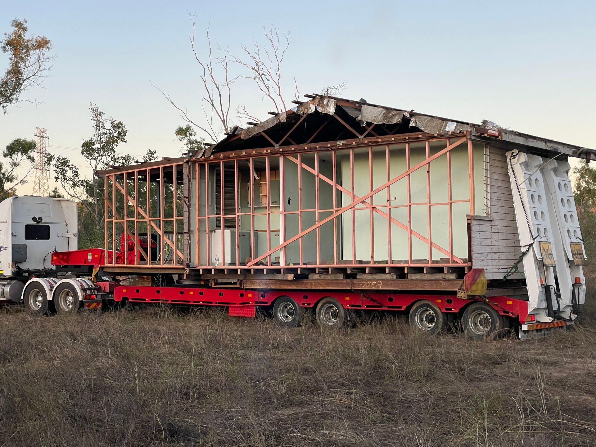 A Truck Is Carrying a House on A Trailer in A Field — Conan The House Lifter In Townsville, QLD