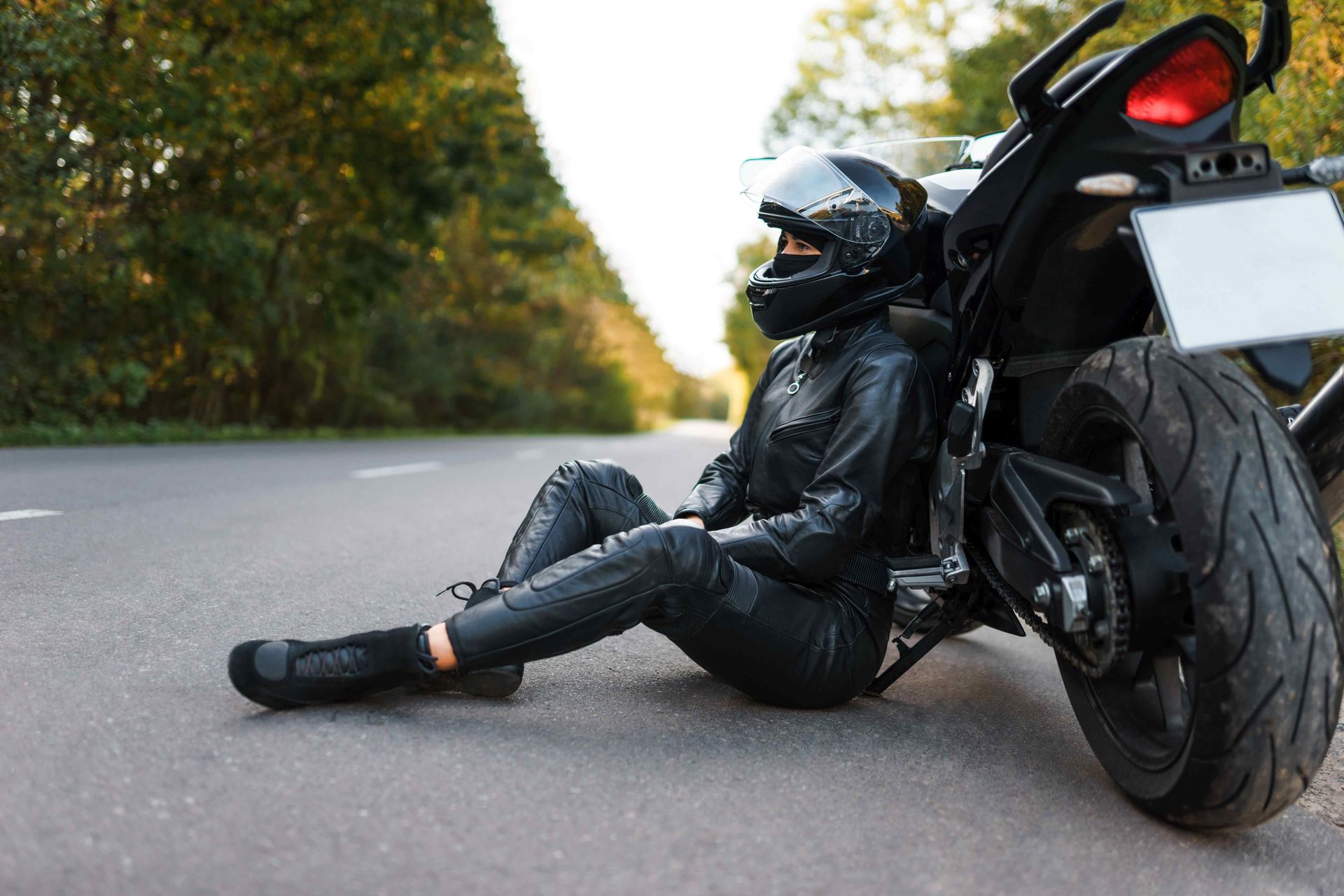 A female sitting against her motorcycle on the side of the road looking out into the horizon. Clicking on this picture will take you to the Motorcycle Accidents page.