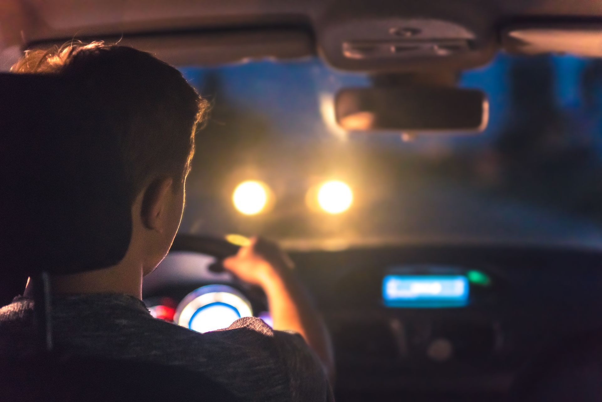 Driver navigating dark road at night with bright headlights ahead, showing nighttime driving visibility risks