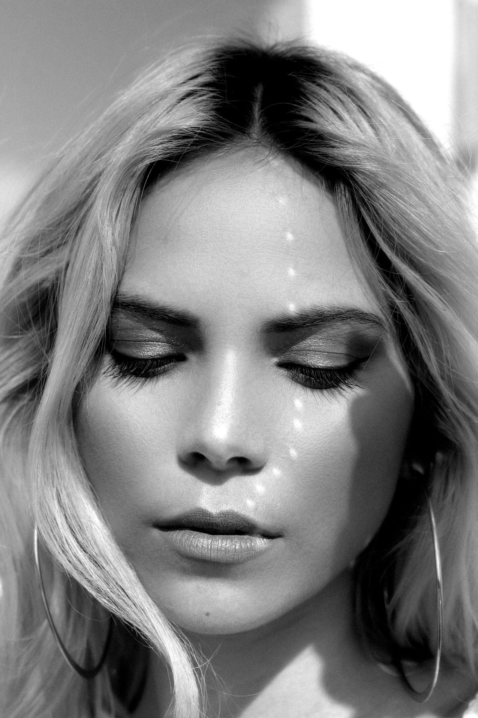 Uma foto em preto e branco de uma mulher com os olhos fechados.