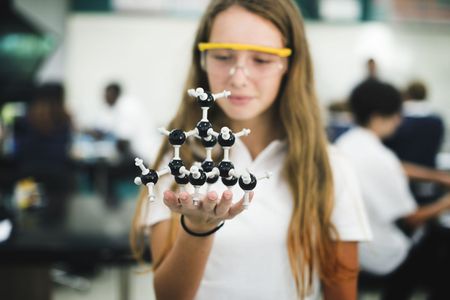 A girl is holding a model of a molecule in her hands.