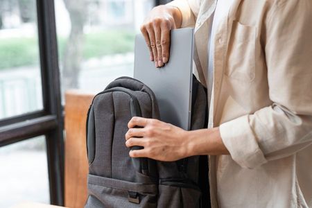 A person is putting a laptop into a backpack.