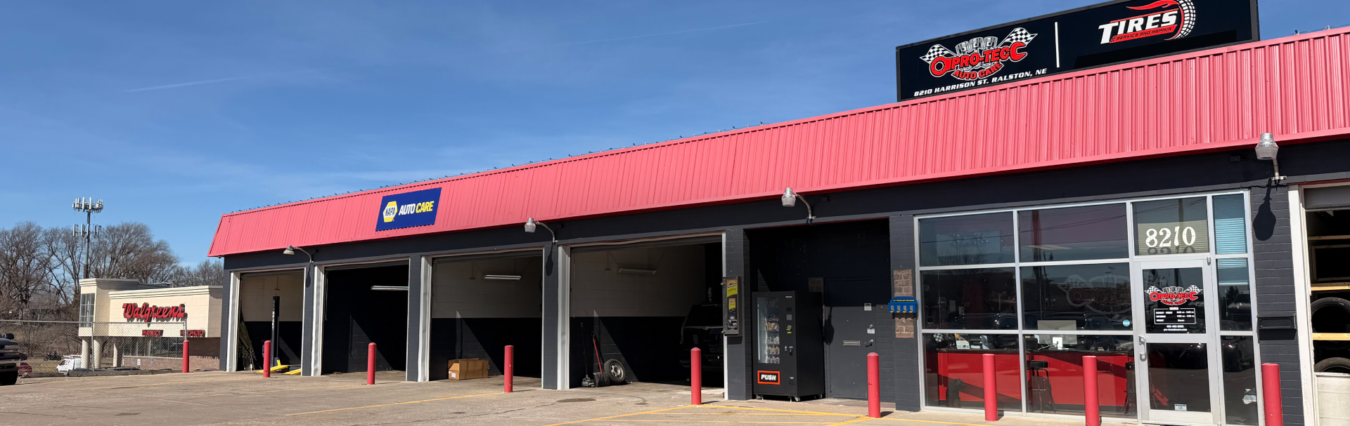An auto service building with a bright red roof and white-and-black signage under a clear blue sky | Pro-Tec Auto Care