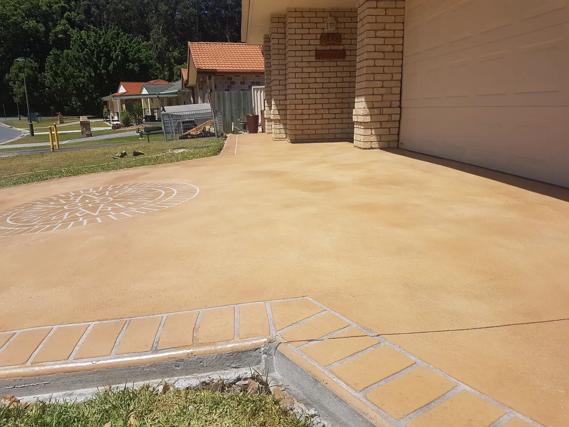 Brown concrete driveway with brick border and garage.