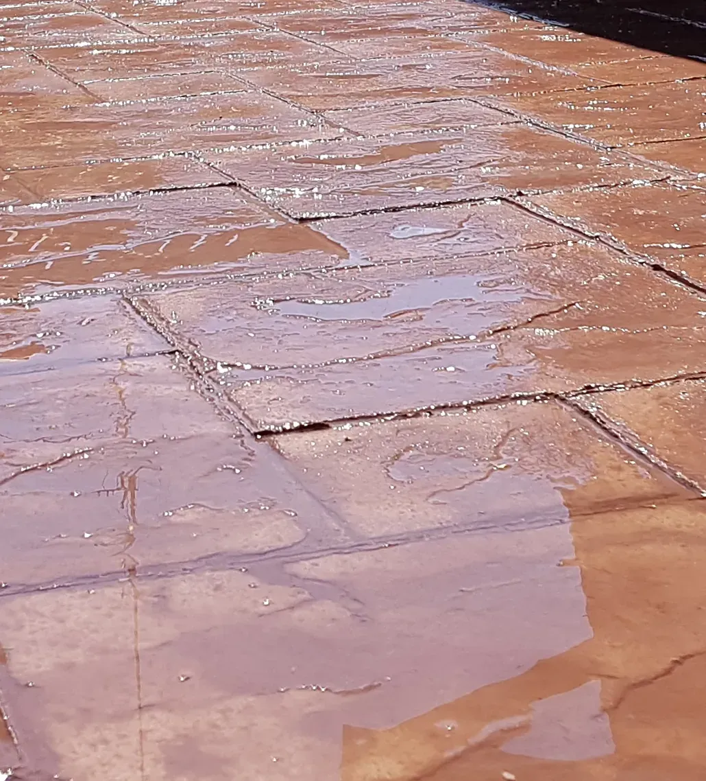 Brown tiled patio surface with water pooling, creating reflections.
