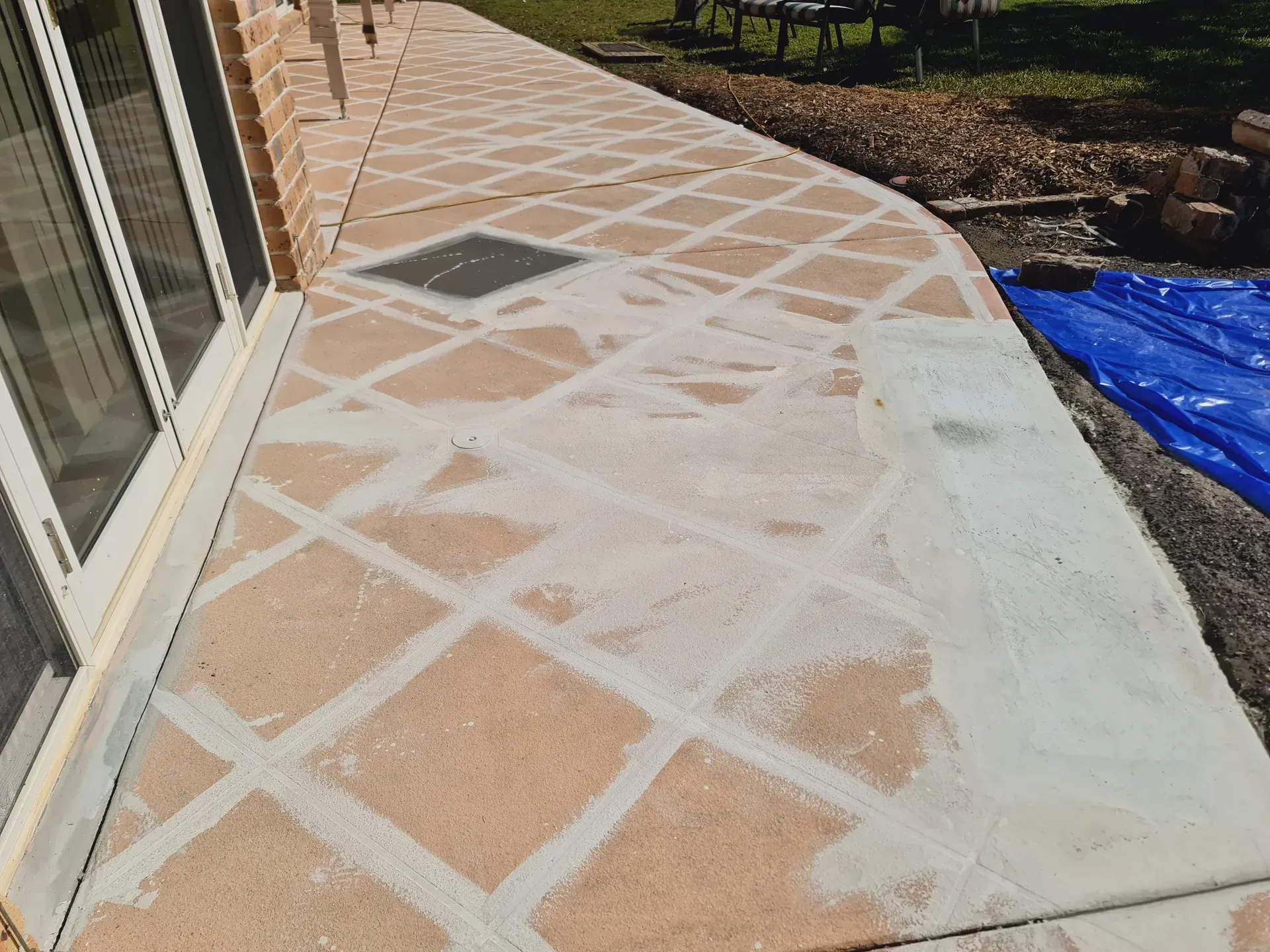 Brick patio with diamond pattern, mortar filled. Light-colored mortar, tan bricks.