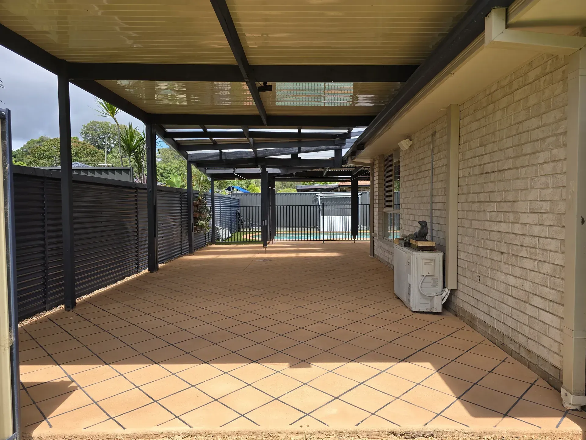 Covered patio with tan floor tiles and a brick wall.