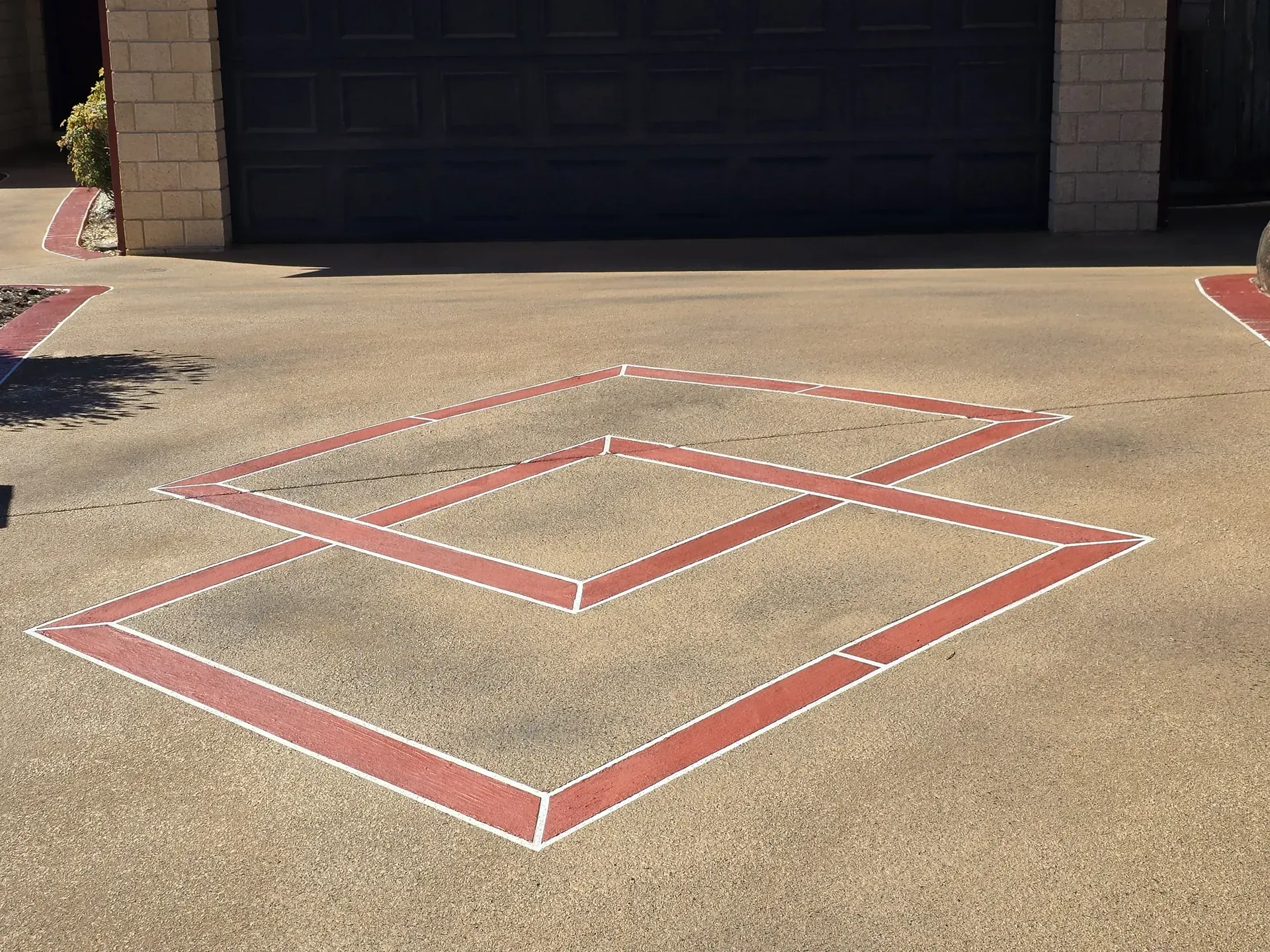 Driveway with red and white geometric design in front of a garage.