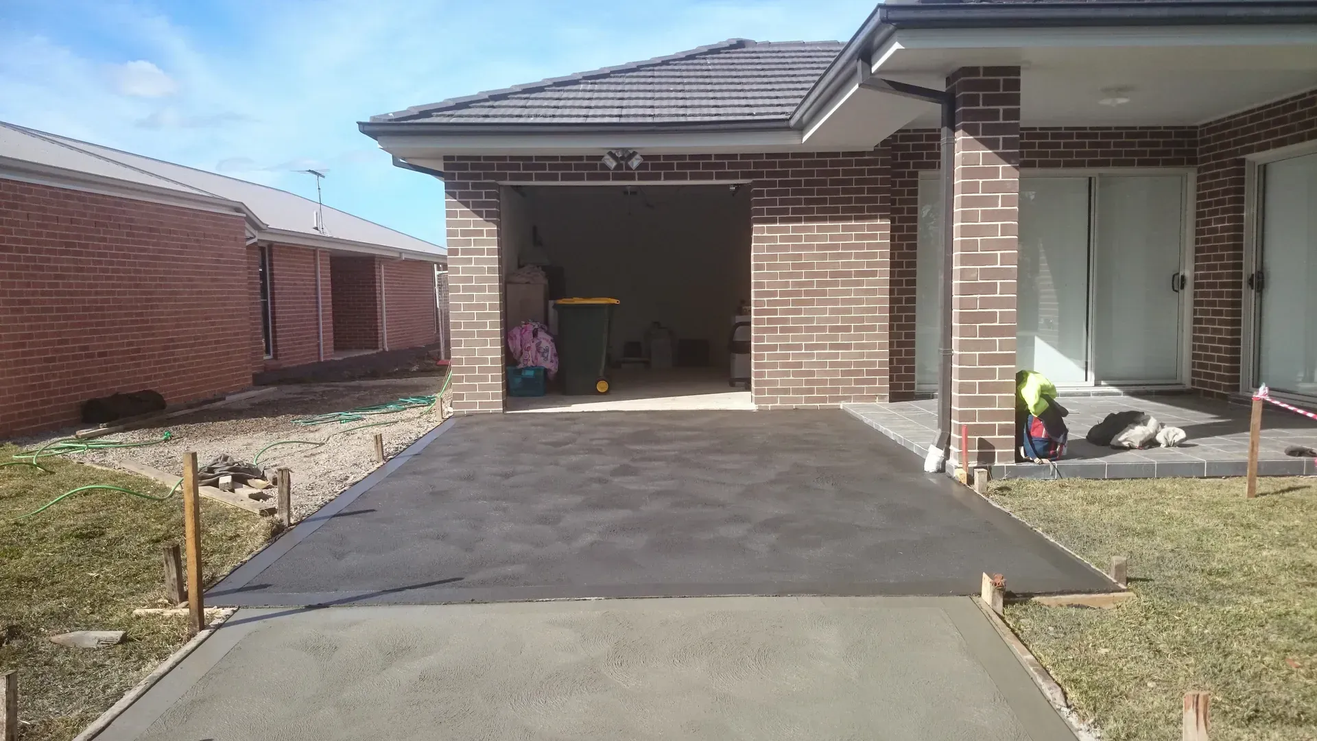 Newly poured concrete driveway leading to a brick garage.