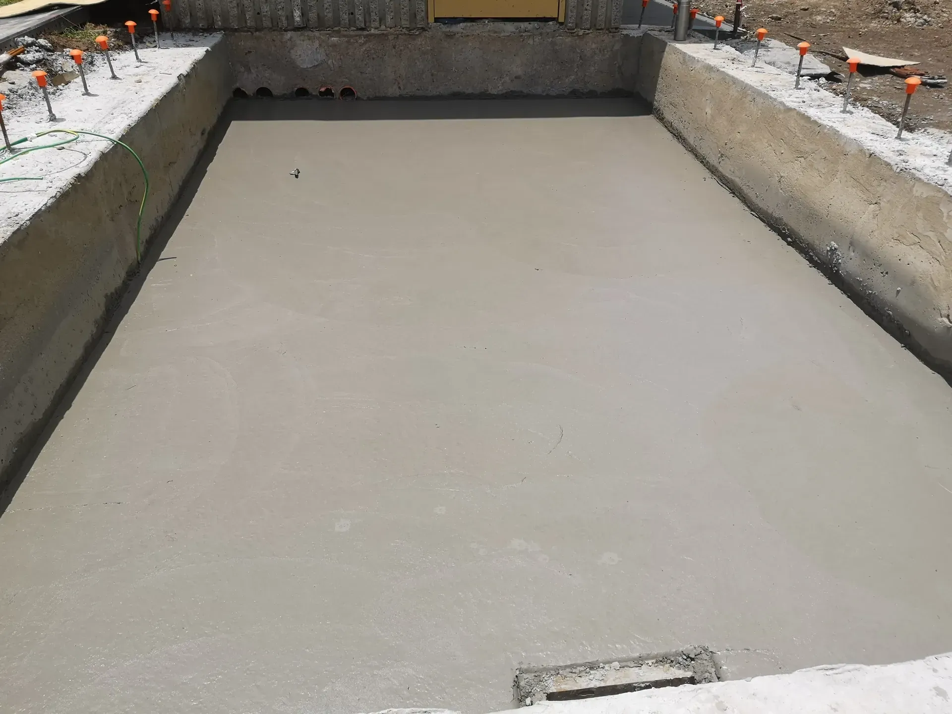 Freshly poured concrete in rectangular formwork, possibly for a pool, outdoor setting.